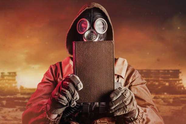 istock Stalker soldier in soviet gas mask holding closed old book. 1298445050
