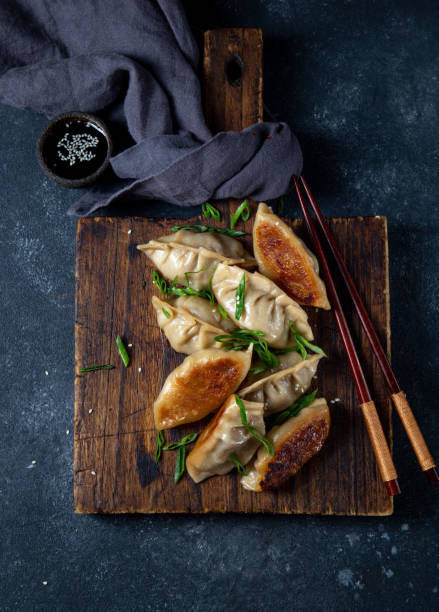 Asian dumplings Gyoza potstickers on old wooden board. Top view, copy space Asian dumplings Gyoza potstickers on old wooden board. Top view, copy space. chinese dumpling stock pictures, royalty-free photos & images