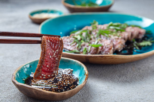 tataki de boeuf avec sauce et sésame sur plaque bleue. cuisine japonaise - tuna steak grilled tuna food photos et images de collection