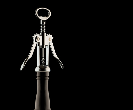 Metal corkscrew on a bottle isolated on a black background. Blank space.