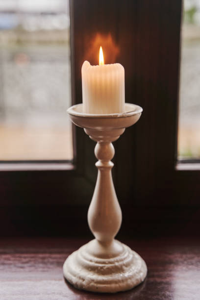 istock A burning candle in a candlestick stands on the windowsill 1298446219