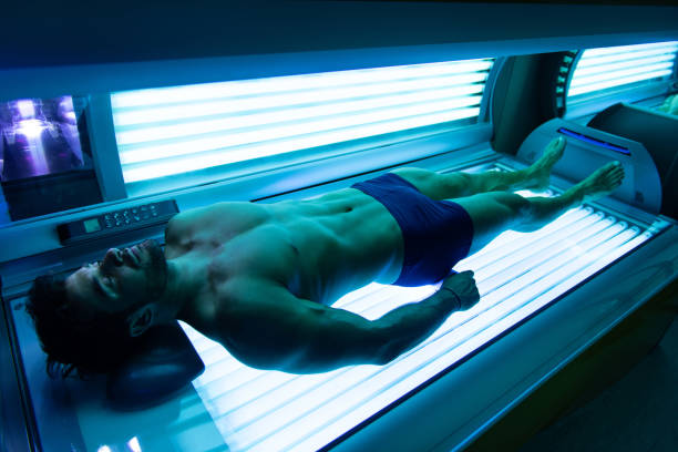 joven hombre musculoso en el solarium en el salón de belleza - cama solar fotografías e imágenes de stock