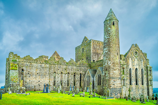 Stock photograph of the cathedral and round tower at Rock of Cashel, Ireland as seen on a cloudy day.