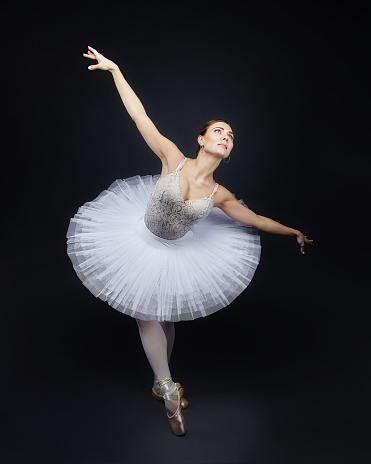 attractive ballerina poses gracefully in the studio on a black background