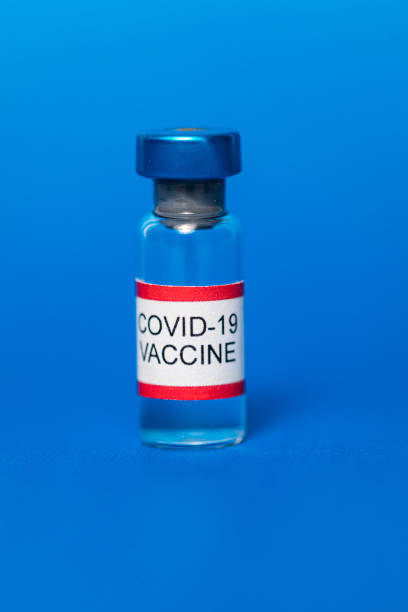 istock Vial filled with Covid-19 vaccine on blue background. 1298468673