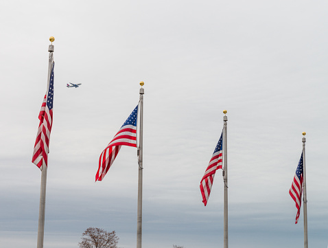 Washington DC, USA - November 30, 2019: Plane flying above several US flags in the National Mall