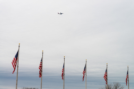 Washington DC, USA - November 30, 2019: Plane flying above several US flags in the National Mall