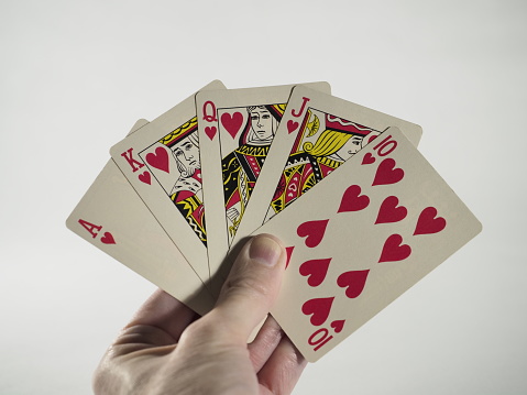 Part of human hand holding cards playing games around wooden table social recreational pursuit cards dealt card games.