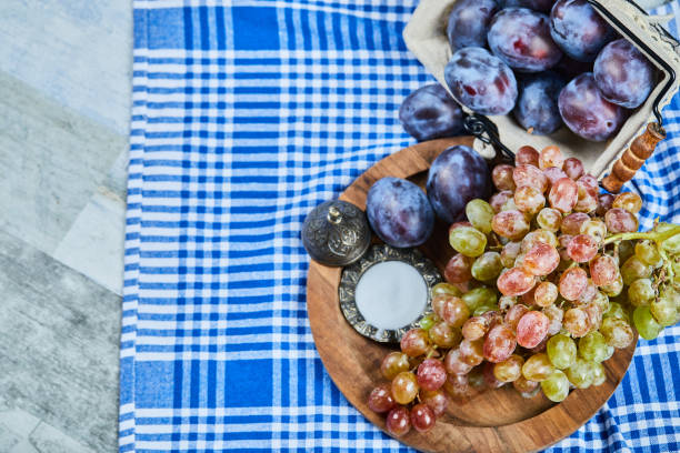 Fresh plums and a bunch of grapes on a tablecloth. High quality photo