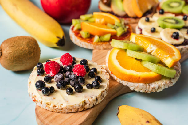 istock Crispy puffed rice cakes on table with fresh fruit kiwi banana apple blueberries raspberries and orange on the table - close up view on healthy organic vegetarian or vegan breakfast gluten free 1298481735