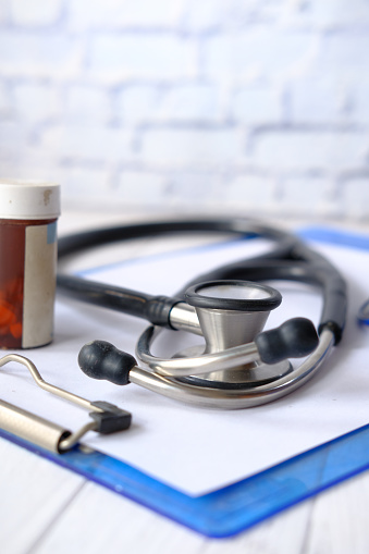 pill container and stethoscope on wooden table ,