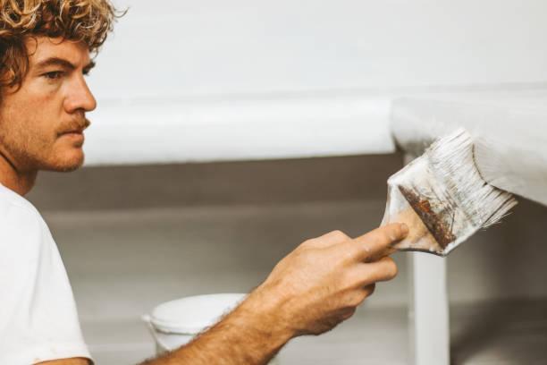 istock Man painting wood with white color 1298482233