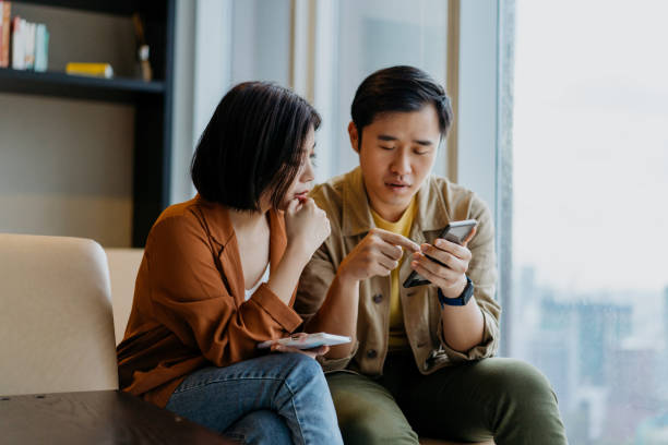 Asian Chinese couple looking at smartphone and having a discussion