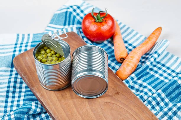 istock Two cans of boiled green peas, vegetables and tablecloth on a white background 1298485171