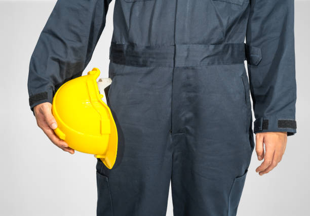 istock Close up Worker standing in blue coverall holding hardhat 1298487992