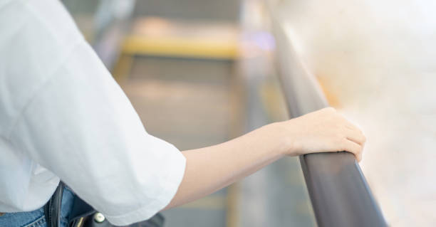 istock Female hand touching escalator handrail while using escalator in shopping mall or public area for moving to another floor. 1298488039