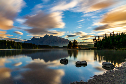 Two Jack Lake at daybreak, starry sky and colorful clouds reflected on the water surface. Beautiful landscape in Banff National Park, Canadian Rockies, Alberta, Canada.