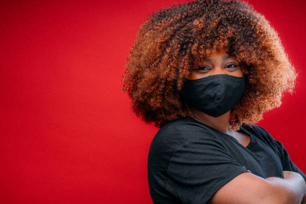 istock Young African American Woman Smiling Under a Cloth Protective Face Mask 1298494446