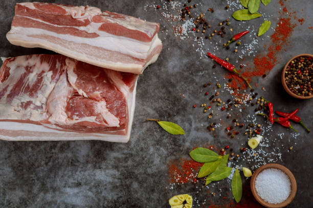 istock Fresh raw pork belly pieces on dark background with spices. 1298500995