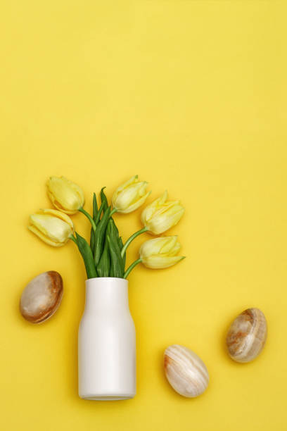 istock Blooming yellow flowers tulip and easter eggs with stone texture on monochrome background with copy space. Spring flowers for holiday. Flat lay. 1298503593