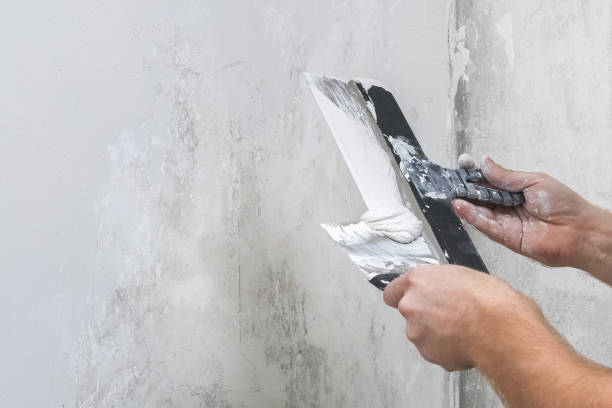 istock A male worker spreads the putty mixture and flattens wall. 1298510323