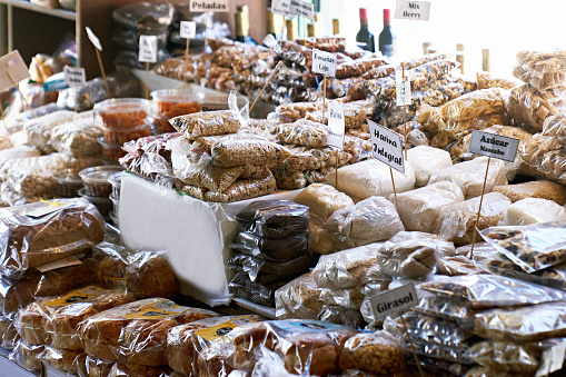 Packages of nuts, sugar, flour, bread, and other grocery items arranged on display table in specialty store.
