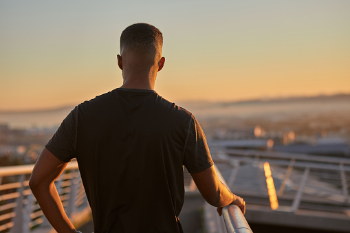 Rearview shot of a sporty young man looking thoughtful while exercising outdoors