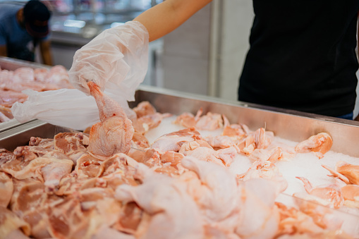 Close up of hand of a woman choosing fresh chicken meat in supermarket