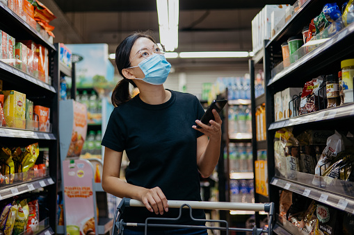 Image of an Asian Chinese woman wearing protective face mask shopping for groceries in supermarket