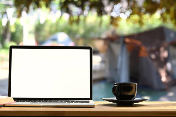 istock Laptop on folding picnic table  near camp tent outdoors. Blank screen for text message or information content. 1298519234