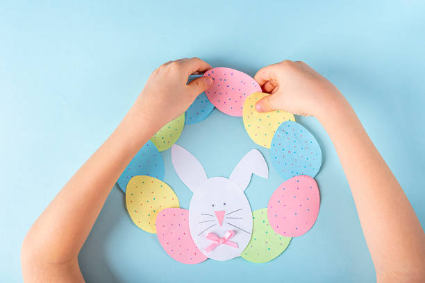 istock DIY and kids creativity. Step by step instruction: how to make paper easter wreath. Step9 glue paper eggs and bunny to circle like wreath. Childrens handmade Easter craft. 1298522759