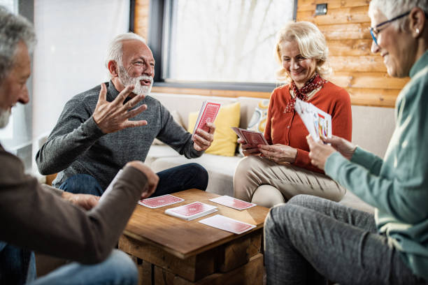 istock Happy senior friends enjoying while playing cards at home. 1298523209