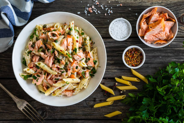 istock Pasta with salmon and vegetables on white background 1298525585