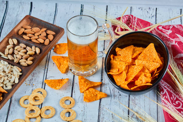 istock Assorted snacks, chips, and a glass of beer on blue table 1298529282