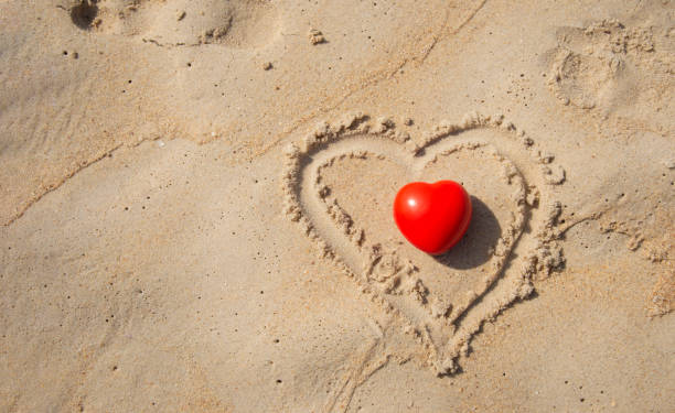 istock Red heart shape on sandy beach by the ocean 1298531021
