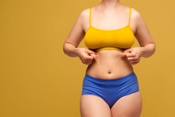 красавица в разноцветное нижнее белье на желтом фоне - overweight tummy tuck abdomen body стоковые фото и изображения