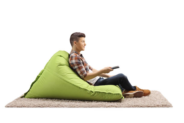 istock Guy sitting on a green bean bag armchair and holding a remote control 1298537828