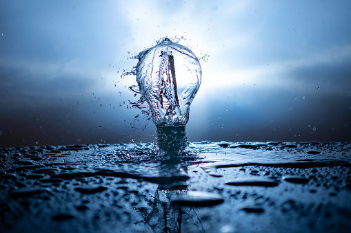Light bulb with water splashes on a bright background