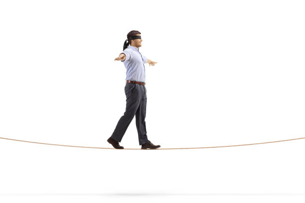 istock Professional man with blindfold walking on a rope and spreading arms 1298543919