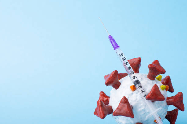 istock Coronavirus model and a syringe with vaccine against blue background 1298546418
