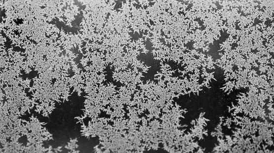 Ornamental hoarfrost pattern on the window glass. Crystal frozen ice texture