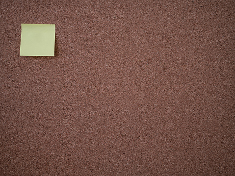 Blank yellow notepaper on corkboard