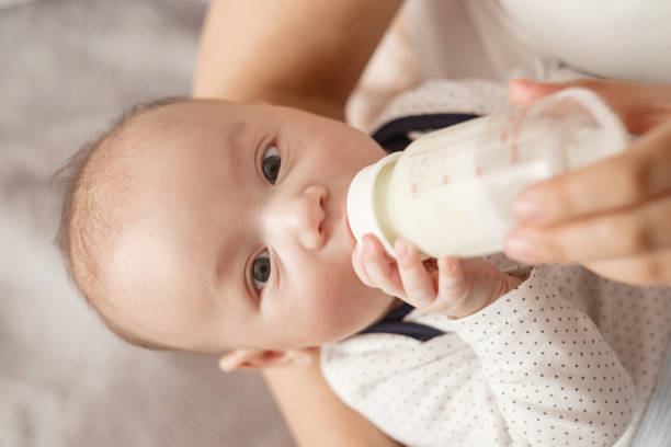 istock baby eats milk from a bottle and looks at camera 1298548858