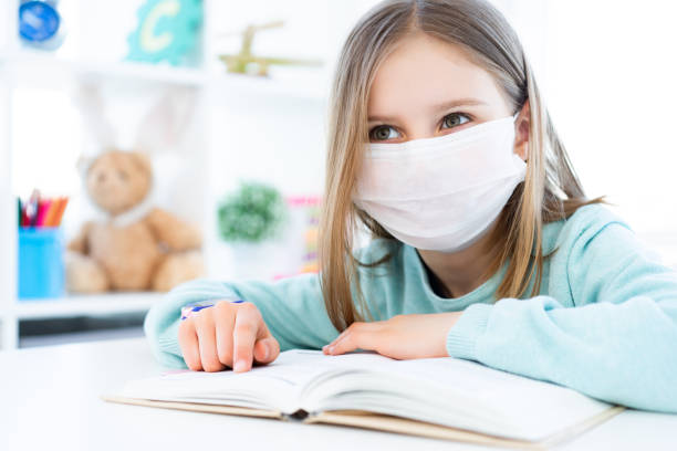istock Little girl in mask reading book 1298552604