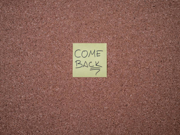 istock Yellow adhesive note with come back text on a bulletin board 1298555009