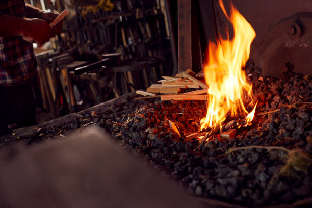istock Male Blacksmith Lighting Wood Kindling To Start Blaze In Forge 1298555371