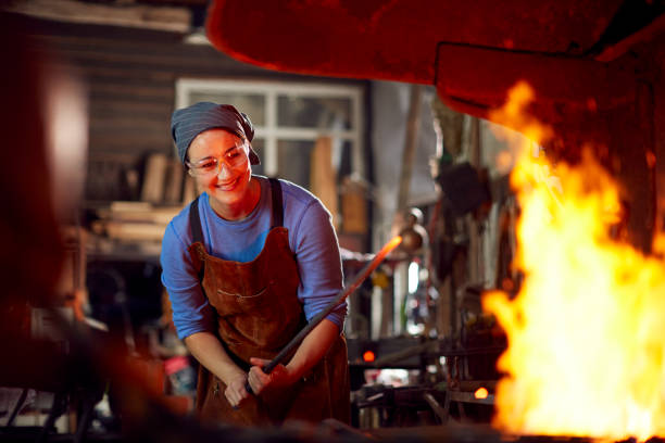 frau schmied heizung metallarbeiten in flammen der schmiede - blacksmith stock-fotos und bilder