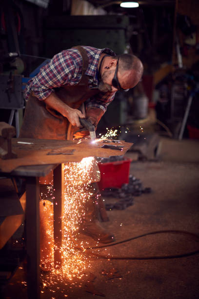 istock Male Blacksmith Using Plasma Cutter To Cut Shape From Sheet Metal In Forge 1298556147