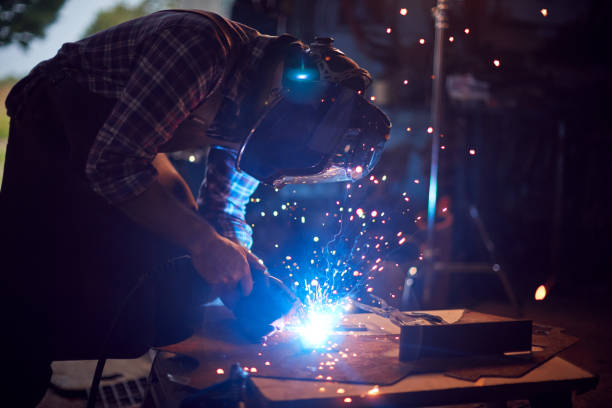 Welding professional showing a welding torch in the workshop. Welder threatening cameraman with welding torch