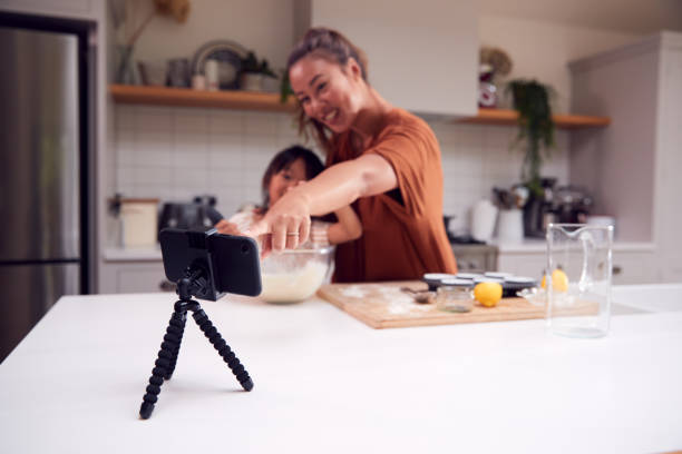 istock Asian Mother And Daughter Baking Cupcakes In Kitchen At Home Whilst On Vlogging On Mobile Phone 1298559126